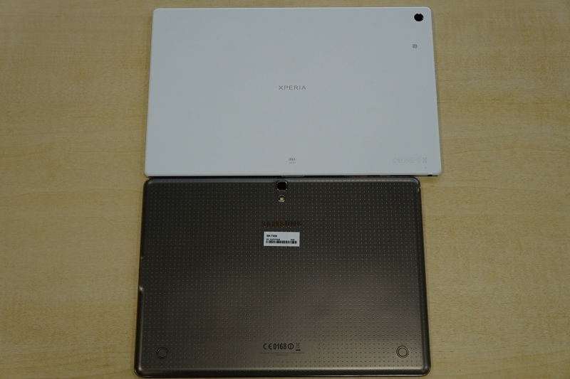 裏面です。写真上のXperia Z2 Tabletは、NFC対応のため、NFCアイコンが表示されています。カメラの位置が、Xperia Z2 Tabletは上部の角、GALAXY Tab Sが上部中央となっています。