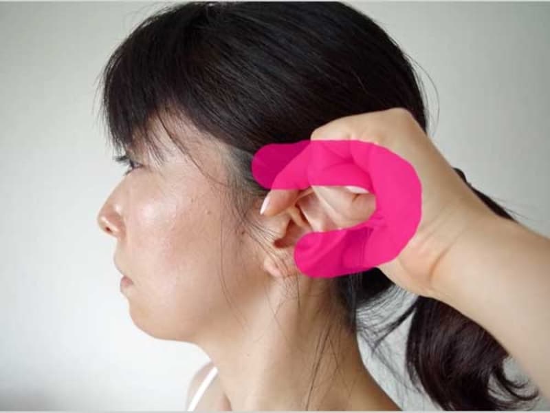 耳に指をかけて側頭部を押す