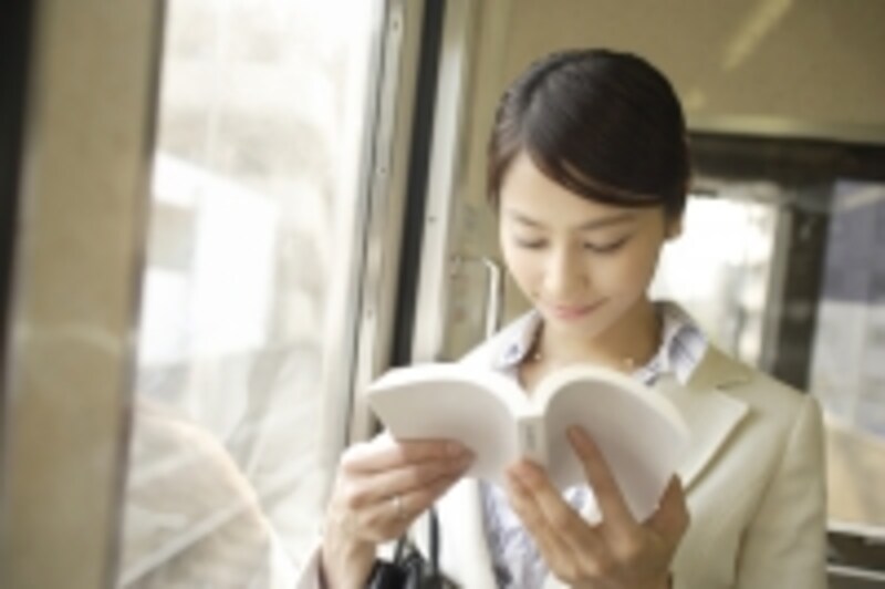 電車で立って本を読んでいる風景
