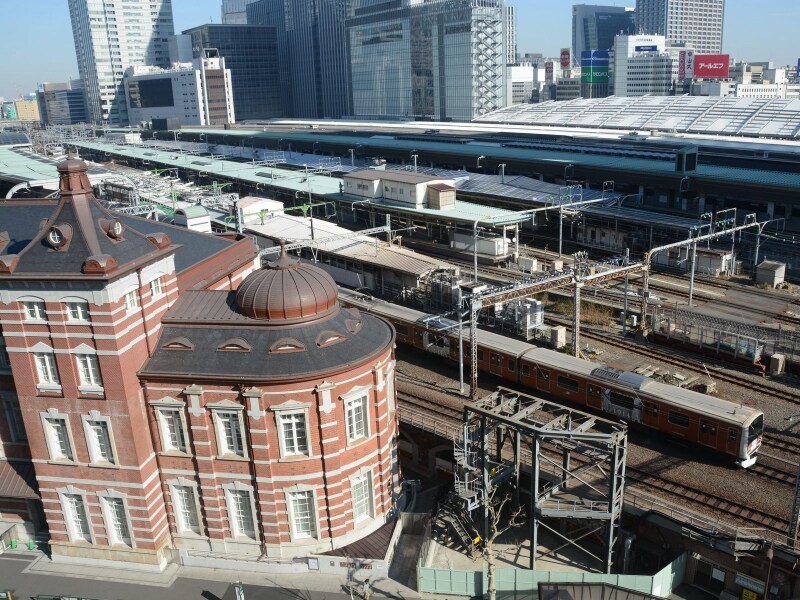 赤レンガ駅舎の脇を走るラッピング車両