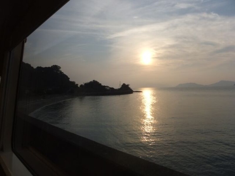 肥薩おれんじ鉄道の車窓（たのうら御立岬公園－上田浦間）／八代海（不知火海）と夕陽