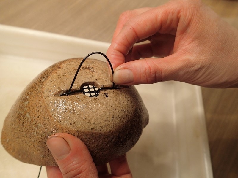 根留めの針金を鉢裏から通しているところ