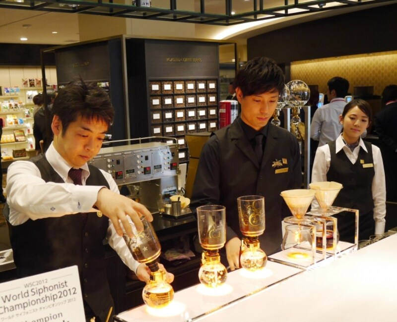 サイフォンとペーパーを使ってコーヒーを淹れるスタッフ
