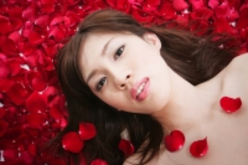 真っ赤な花びらの上に寝転ぶ女性