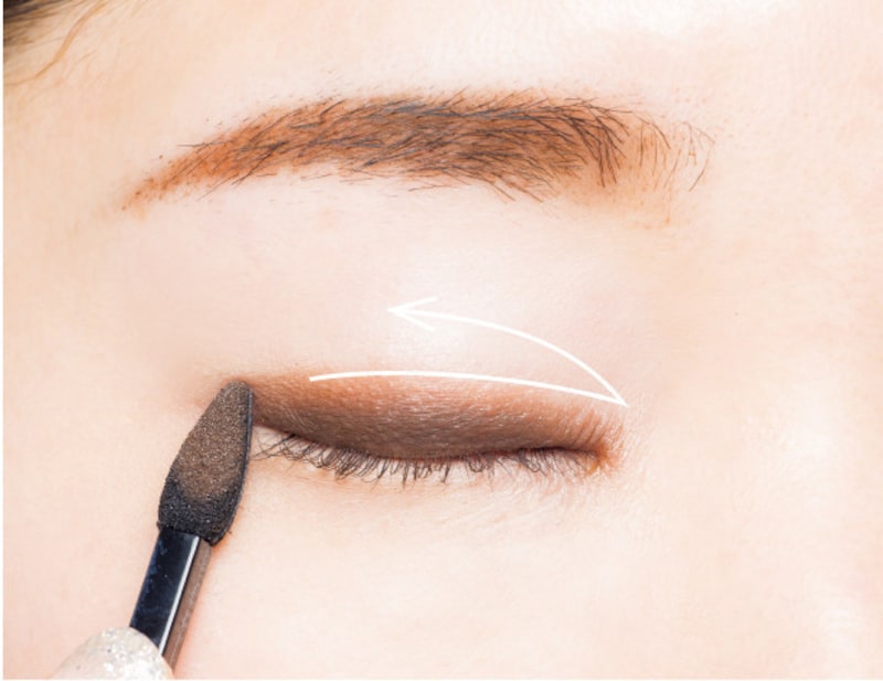 ワイパーのように左右にチップを動かしてブラウンのアイシャドウを塗る