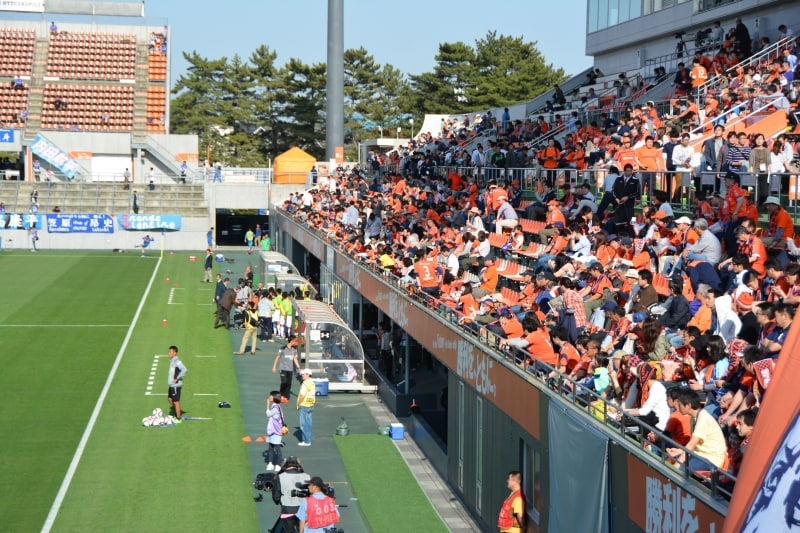 真下からプレーヤーがピッチに走り出すメインスタンド
