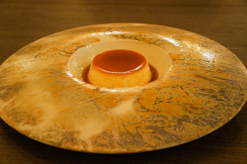 レストランメニューのデザートとしてのプレゼンテーション。お皿は、卵とミルク、そして砂糖が混ざり合う様子を表現。