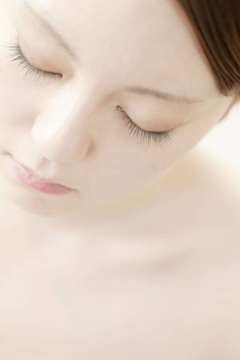 目をつむってうつむいている女性