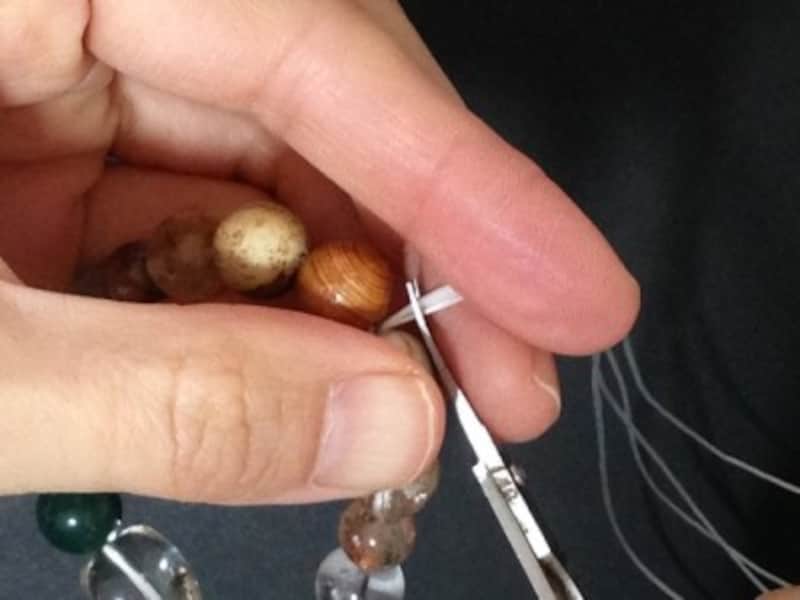 中央の茶色い木玉に結び目を入れます