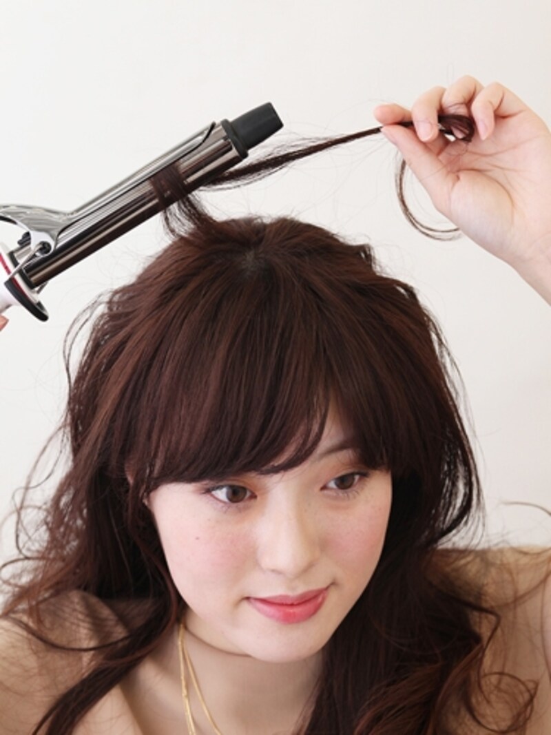 ヘアアイロンで全体を巻く。ハチ上の髪は細いロットで