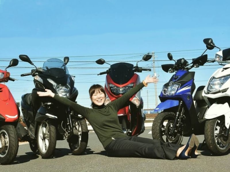 ヤマハの125ccスクーターに囲まれる菊地さん。めっちゃ笑顔！