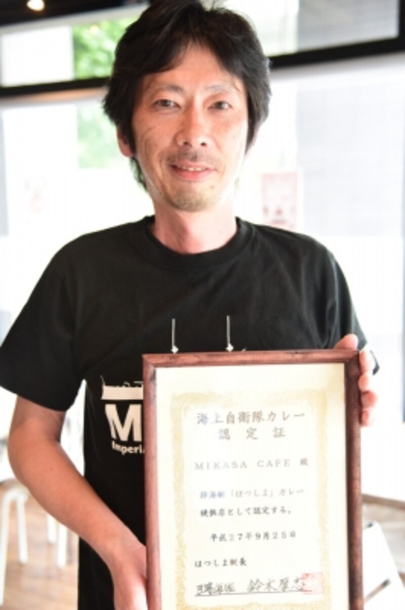 「MIKASA CAFE」店長の一本和良さん。手にする認定証は、平成27年9月に開催された「横須賀海上自衛隊カレー認定証授与式」において、海自カレー認定店に授与されたもの