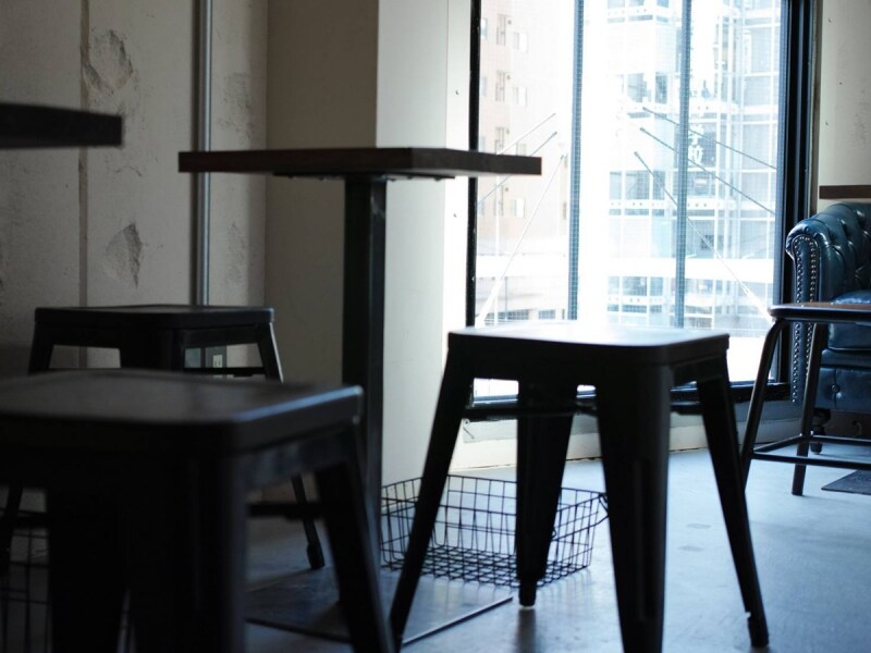 コンクリートの打ちっ放しの壁面とシンプルな椅子、テーブルの端然とした空間