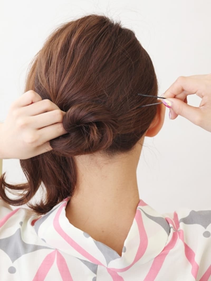 くるくるとねじり上げて、2つシニヨンを作る