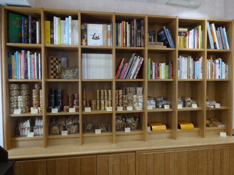 「ラトリエ モトゾー」の焼き菓子の棚には、菓子や料理の専門書がずらりと並ぶ