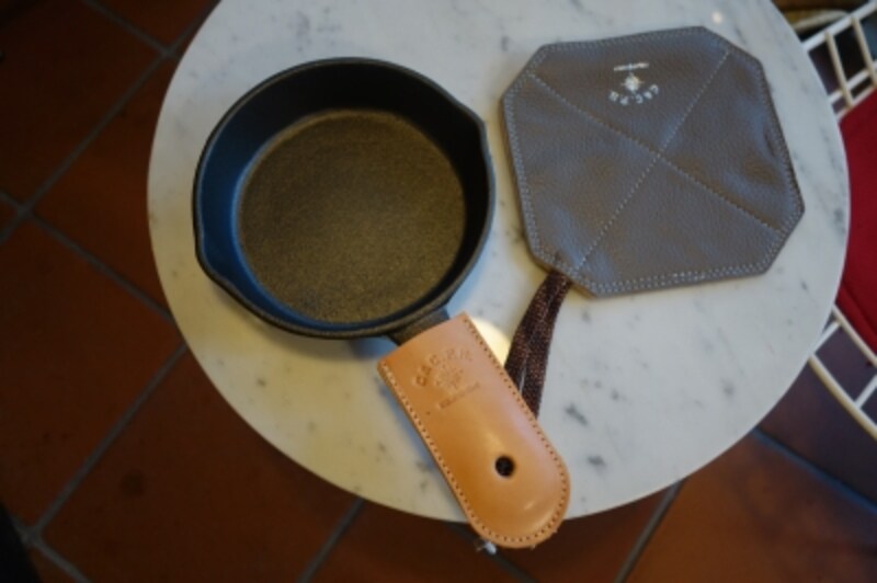 小ぶりのスキレットは人気アイテム。取っ手用レザーカバーとセットで。鍋つかみ兼鍋敷きもシンプルなデザインのものが揃っています。普段は自宅で使ってもOK。