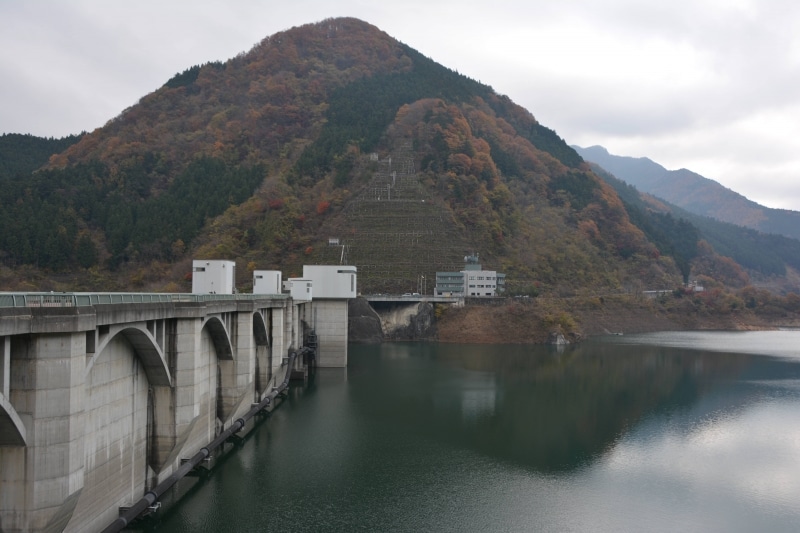 湖岸も湖面も紅葉の色彩で覆われる浦山ダム