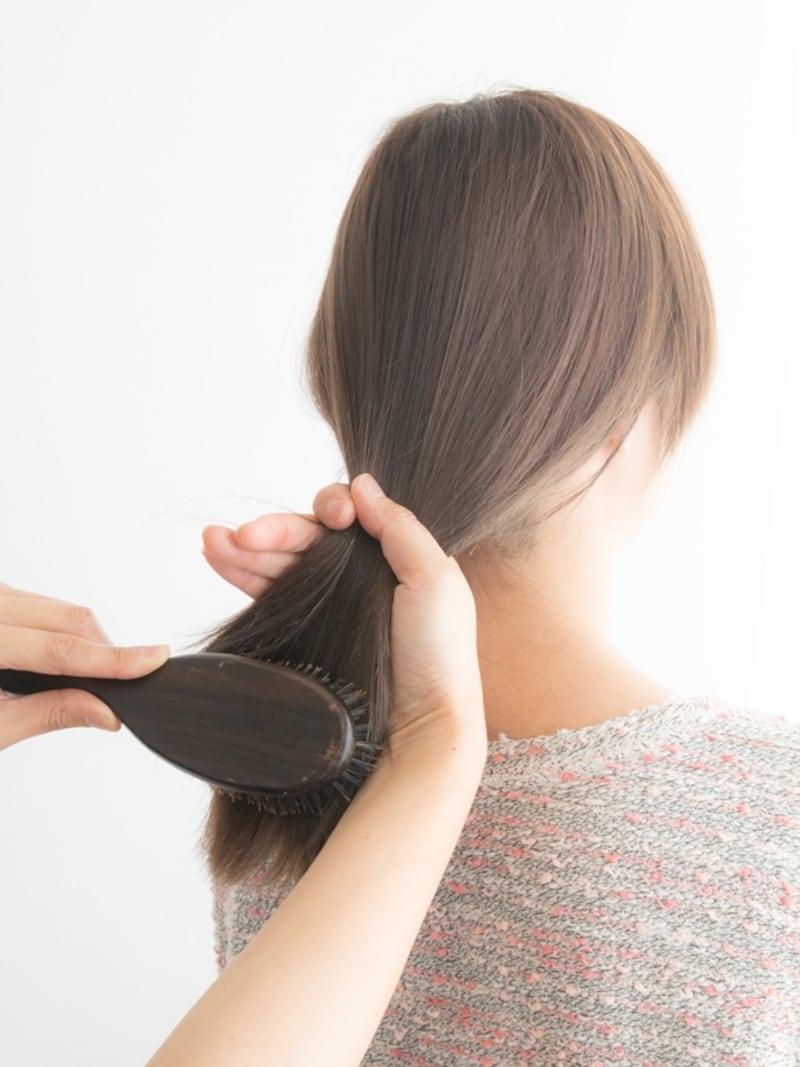 髪を押さえながら毛先をとかす