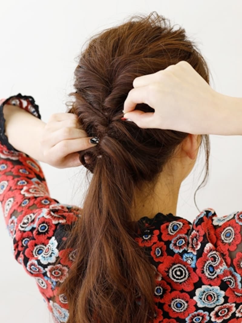 結び目を押さえながら放射状に髪を引き出す