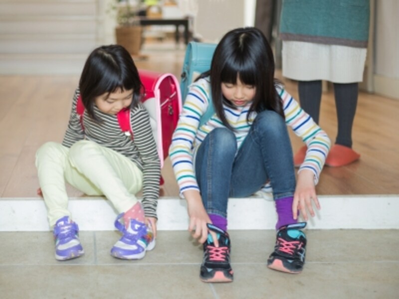 玄関で靴を履く子ども