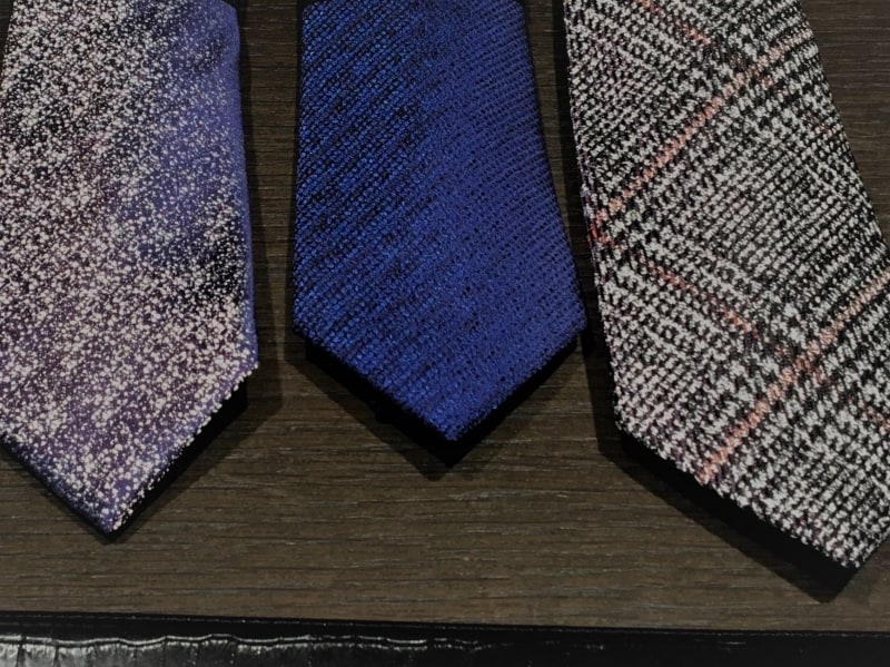 左画像は見る角度によって光沢色が変わるカメレオンネクタイ。また、右画像はウール混紡のネクタイ。これまで定番と言われていたレジメンタルストライプ以外のバリエーションが増えている。