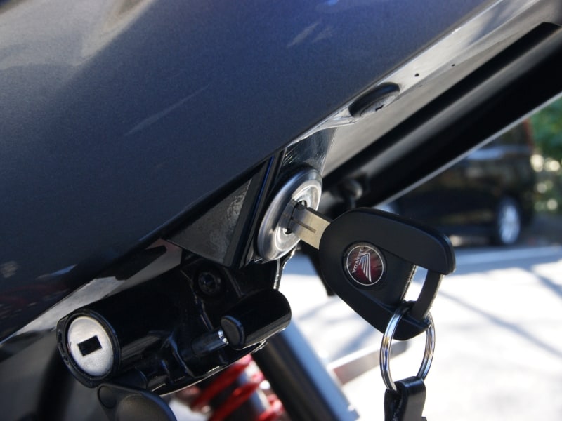 鍵が刺さっているのがシートの開閉装置。左下にあるのがヘルメットロック