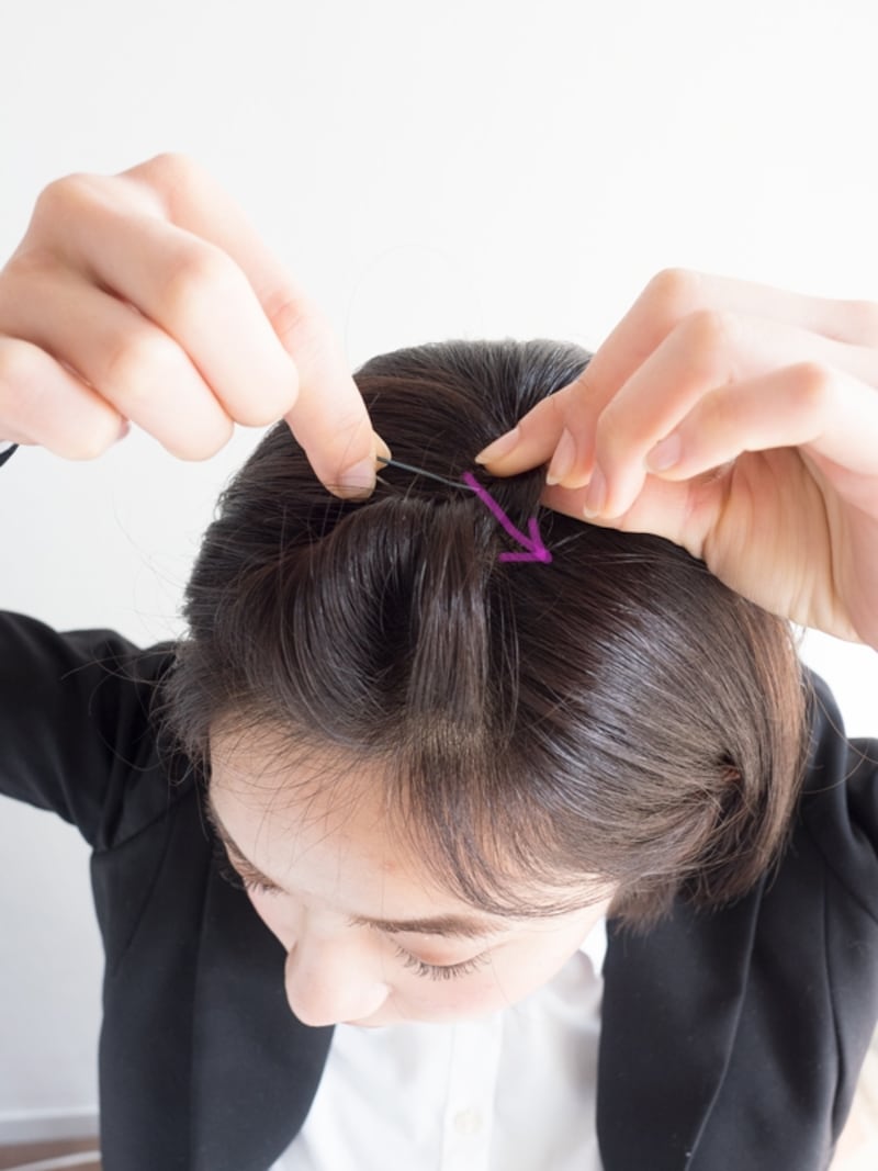 前髪を一回転ねじり、矢印の方向にピンで固定