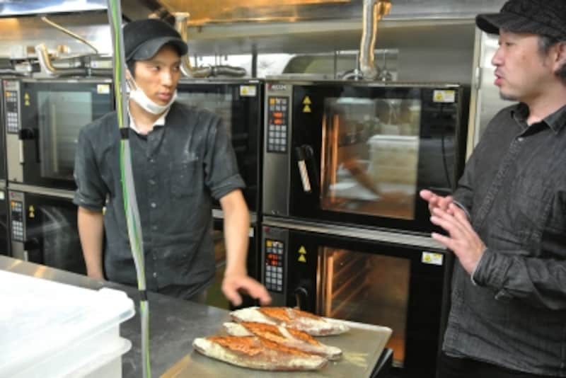 パンをチェックする杉窪さん。厨房にはコンベクションオーブンが並ぶ