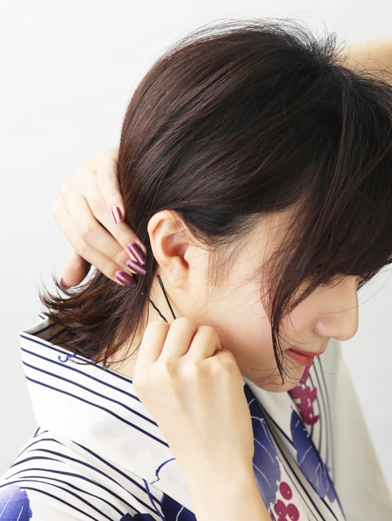 耳の後ろで髪をピン留めする