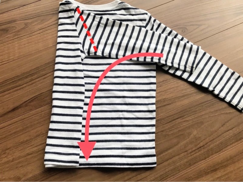 長袖Tシャツのたたみ方・手順2:点線で折り返す。折る部分に手で押さえるとたたみやすい