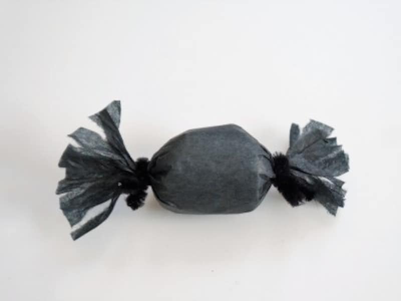 紙の両端を黒いモールでしばります。紙を少し割いてクモの足を作ります。