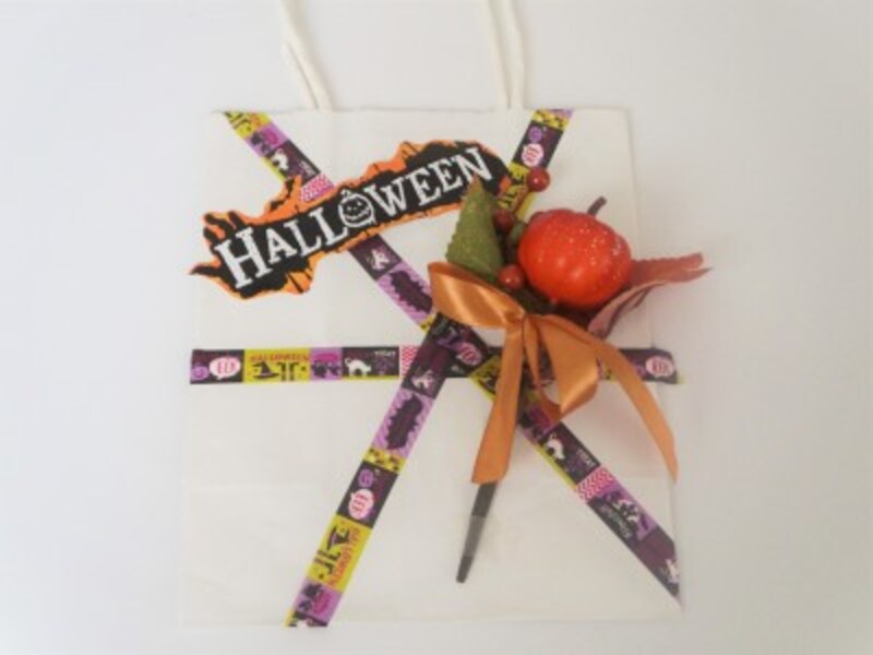 紙袋に造花やプレゼントしたい小物を透明テープでしっかりと留めます。