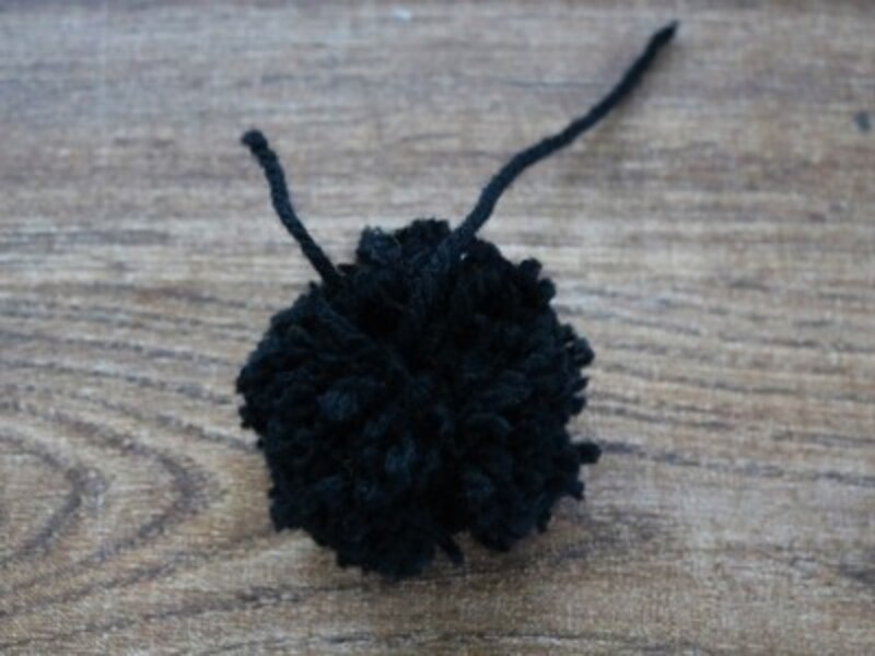 黒い毛糸で一回り大きなポンポンを作ります。