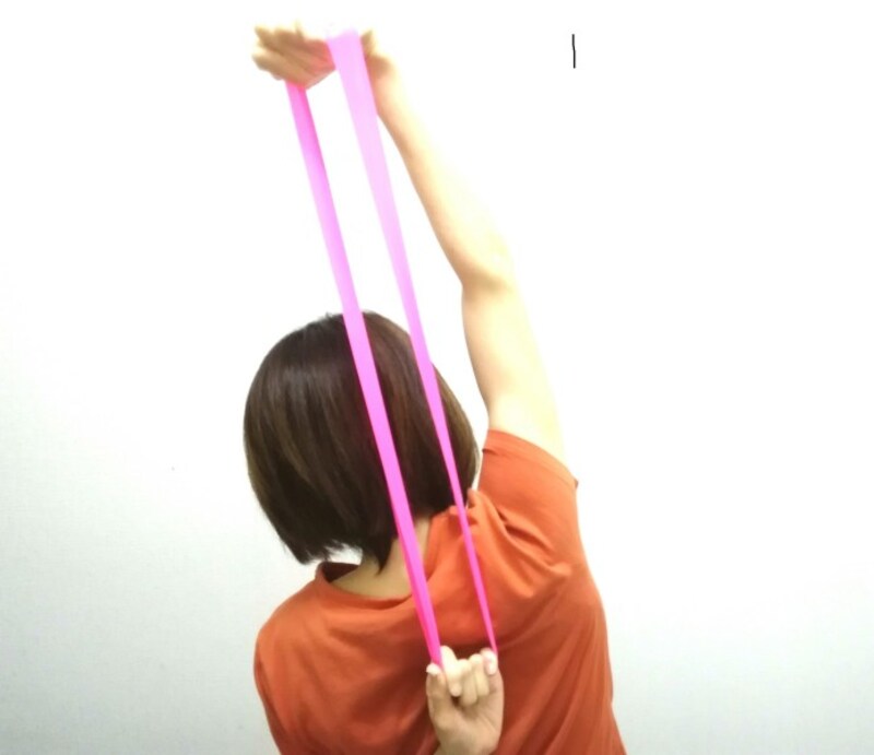 背後でゴムリングを握り、片方の肘を伸ばしながら体を横へ少し倒し肩こり予防をしましょう