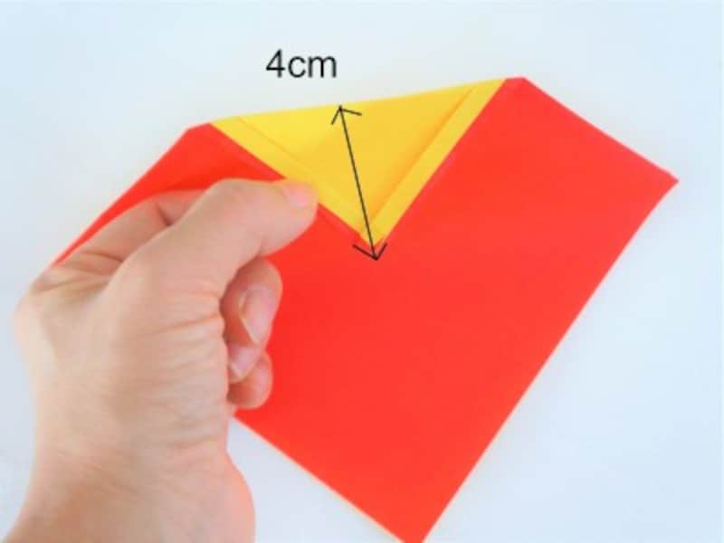 折り紙を裏返し、紙が重なった角を中央に向かって折ります。