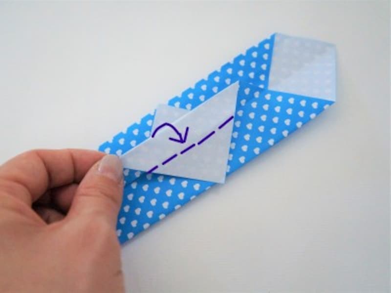 三角の底辺を持ち上げ、半分だけ手前に折ります。