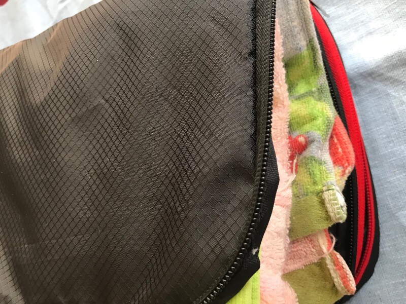 両サイドに衣類をいれて圧縮トラベルポーチのファスナーを閉じる