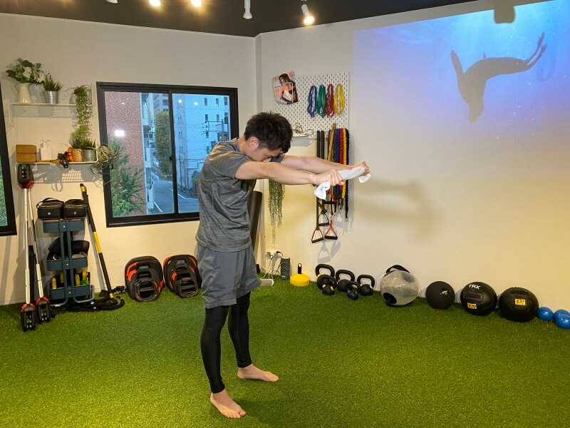 step 1. フェイスタオルを肩幅で持ち、背中を丸めて肩甲骨を大きく広げます。