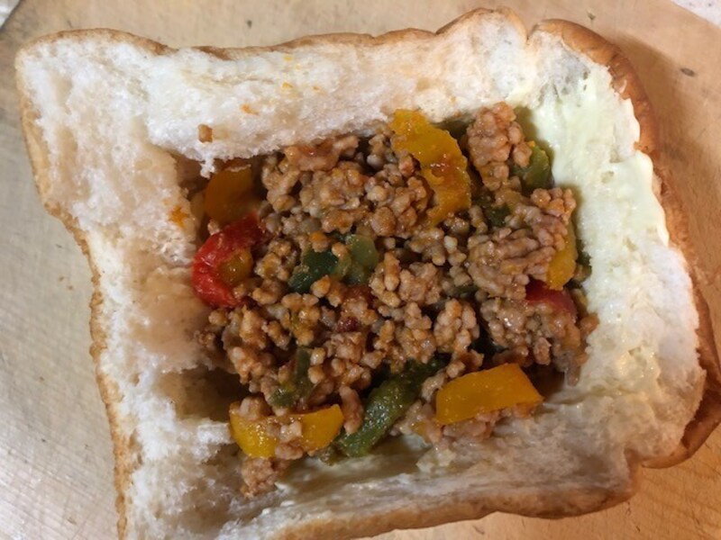 パンの穴に炒めたひき肉をいれる