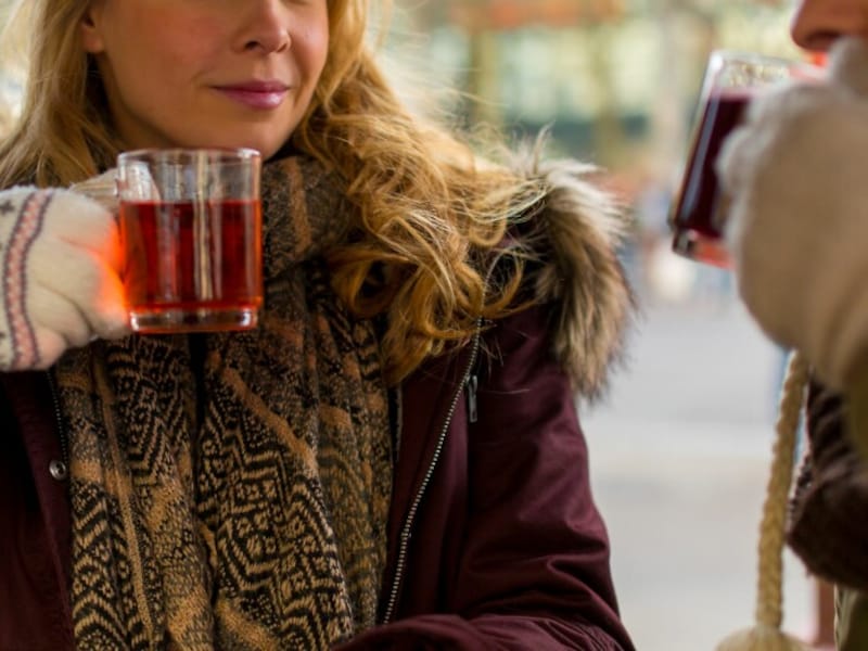 冬の屋外でホットワインを飲む女性