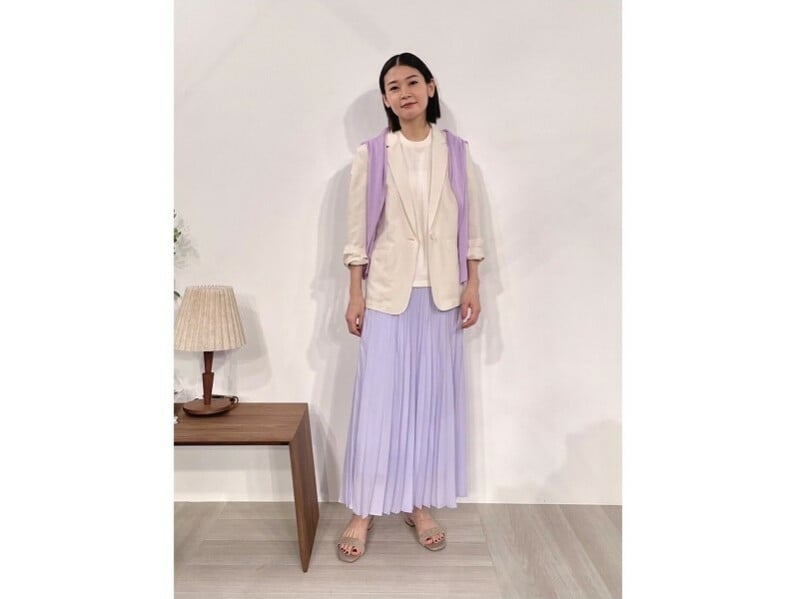 動くたびに揺れるライトパープルのプリーツスカートがフェミニンな印象 出典:StyleHint