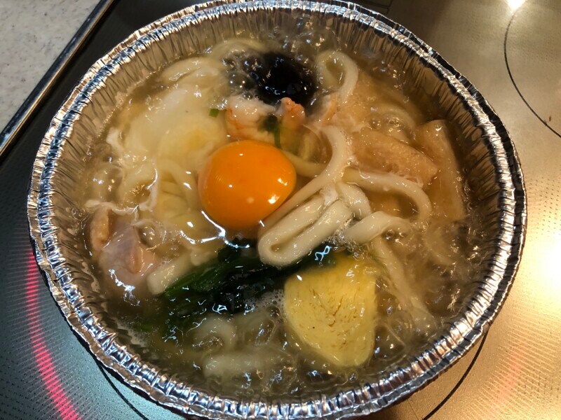 セブンイレブンの「7プレミアム 鍋焼うどん」に卵を落とす