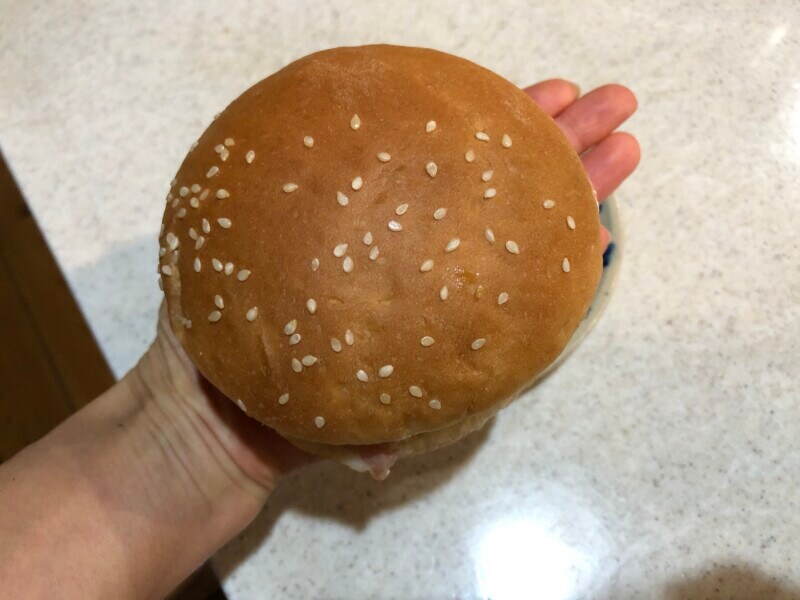 セブンイレブンの「ベーコンエッグバーガー」を女性の手のひらの上に乗せると指先が出るくらいの大きさ