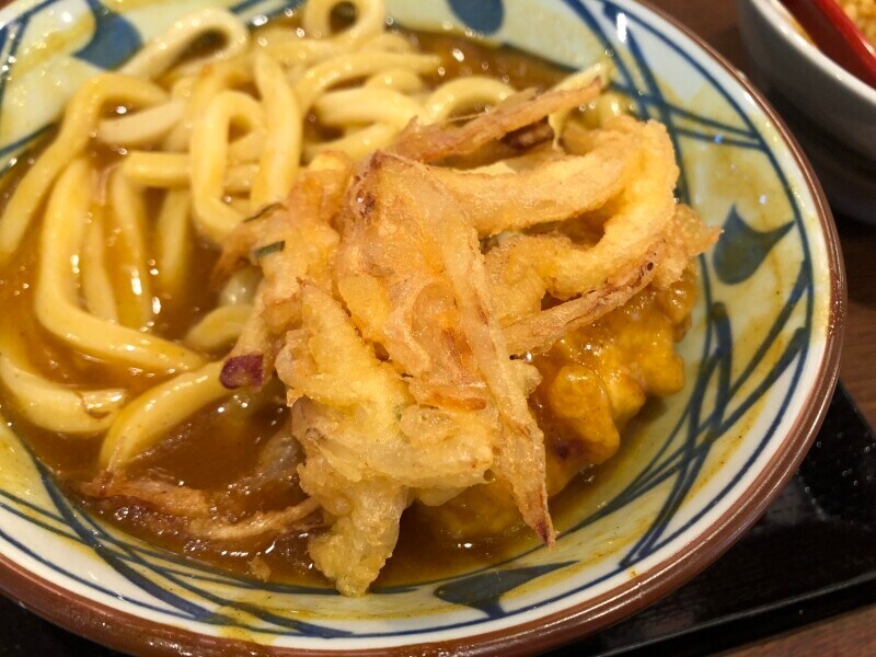 丸亀製麺のカレーうどんに、野菜のかき揚げを乗せる。半分がおすすめ