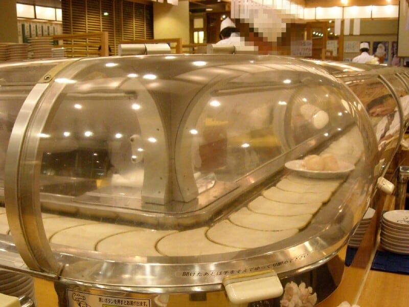 寿司が空気に触れないようにトンネルの中のレーンを通って客席まで届けられる例。画像は筆者撮影