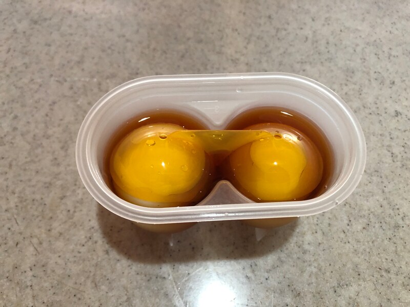 ダイソーの「味付け卵職人（2個用）」にゆで卵と調味料を入れ、落とし蓋をする