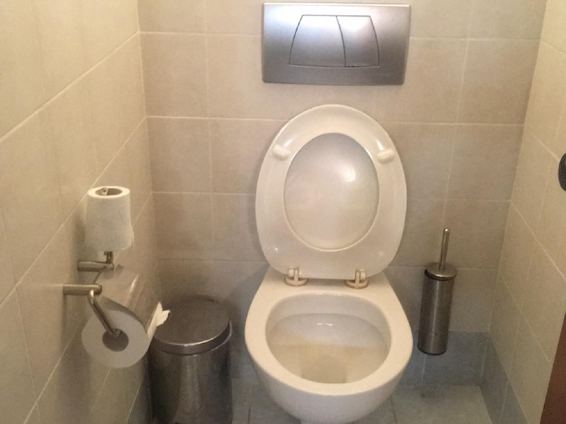 トイレのタンク上に壁付けの水を流すパネルがある