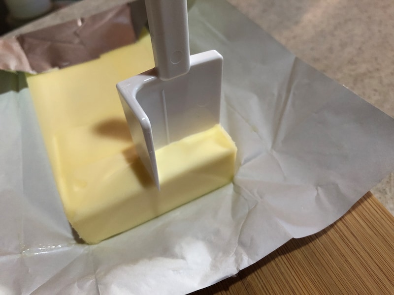 ダイソーの「バターカッター」をバターの端に合わせてグッと押し込む