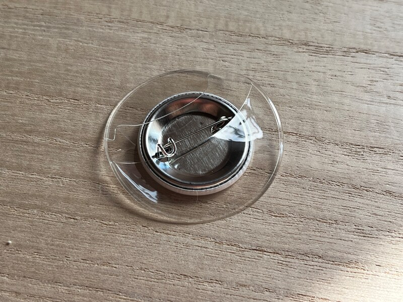 缶バッジを裏にして、下半分をカバーの奥まで入れる