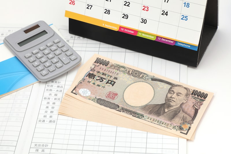 一万円札とカレンダーと電卓